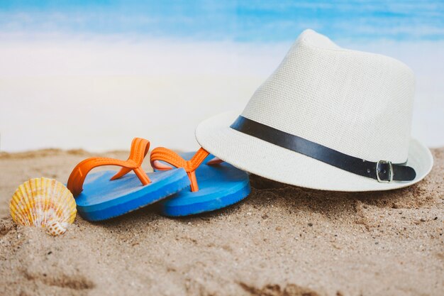 Summer composition with hat, seashell and flip flops