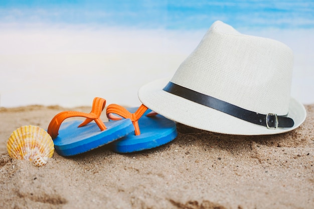 Summer composition with hat, seashell and flip flops