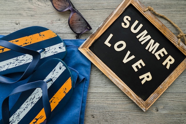 Summer composition with slate, flip flops and sunglasses