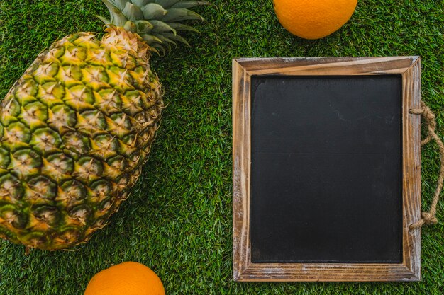 Summer composition with slate, pineapple and oranges