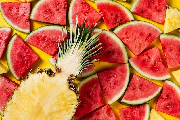 Summer concept. Conceptual. Tasty appetizing slice of pineapple with watermelon slices on yellow bright vibrant background with wooden letters Summer. Flat Lay.