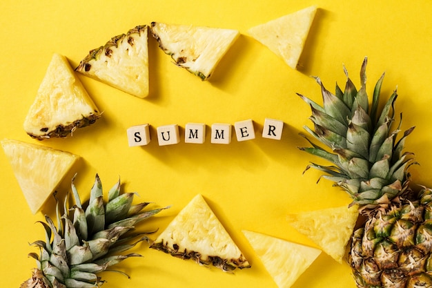 Free photo summer concept. conceptual. tasty appetizing slices of pineapple on yellow bright vibrant background with wooden letters summer. flat lay.