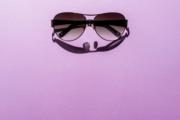 Summer concept with sunglasses on purple background