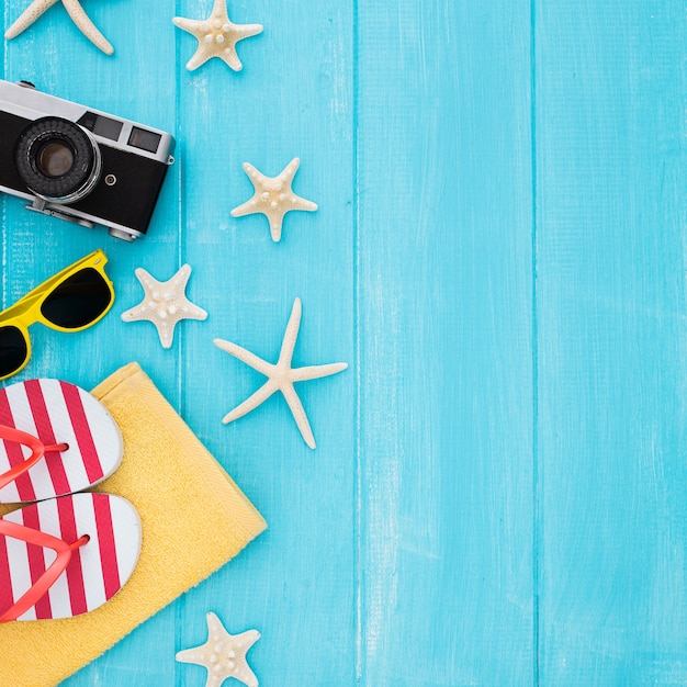 Летняя концепция с винтажной камерой, солнцезащитные очки, полотенце, морская звезда на синем фоне деревянных