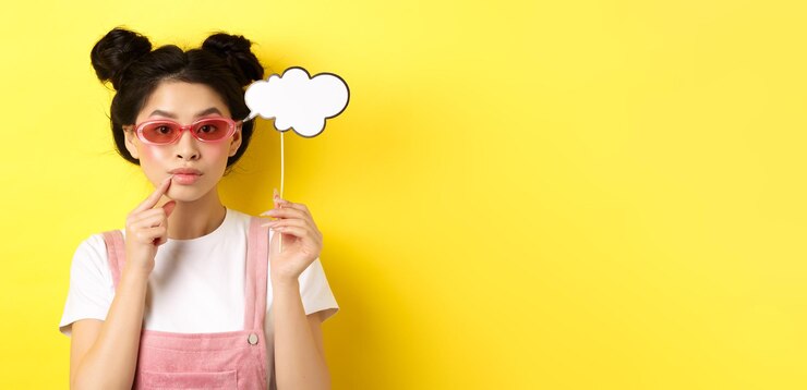 無料Photo 夏とファッションのコンセプト スティックと looki にコメント クラウドを保持しているサングラスをかけたスタイリッシュなアジアの女の子