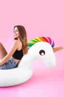 Foto gratuita concetto di moda di estate con la giovane donna sull'unicorno gonfiabile