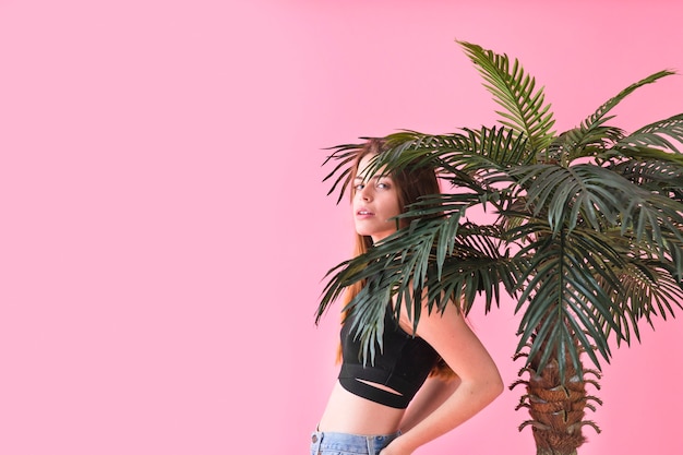 Summer fashion concept with young woman next to palm tree