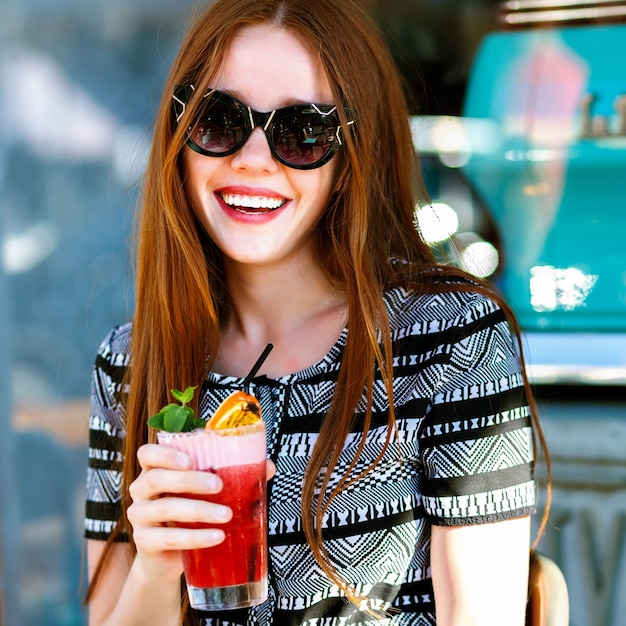 Free photo summer fashion portrait of pretty young elegant ginger woman, sitting at terrace , drinking tasty lemonade, glamour outfit, sunny vacation, relax, joy, natural beauty.