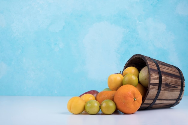 Summer fruits mix out of a wooden bucket on blue.