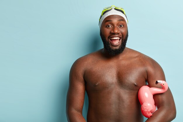 Концепция летних каникул. Веселый спортивный мужчина с темной кожей, смеется и показывает белые зубы