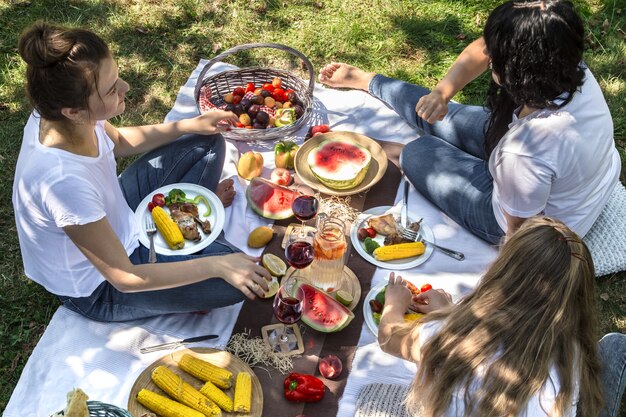 自然の中で友達と食べ物や飲み物を楽しみながら夏のピクニック。