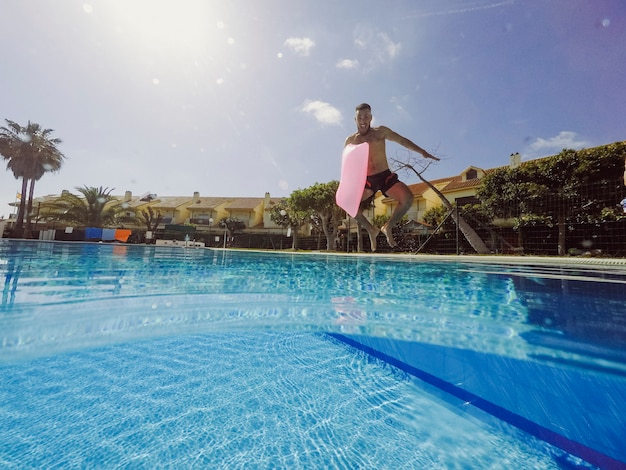 Summer and pool concept with man jumping into pool