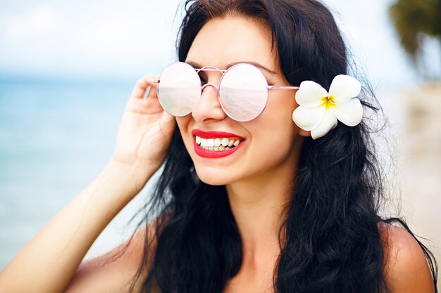 summer portrait is pretty brunette girl posing on perfect lonely tropical island beach, travel and enjoy vacation, bright blue bikini and sunglasses.