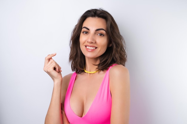 Free photo summer portrait of a young woman in a pink swimsuit bright yellow beach necklace