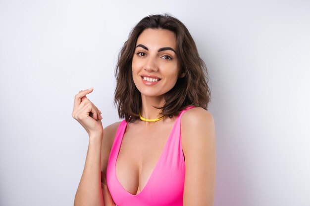Summer portrait of a young woman in a pink swimsuit bright yellow beach necklace