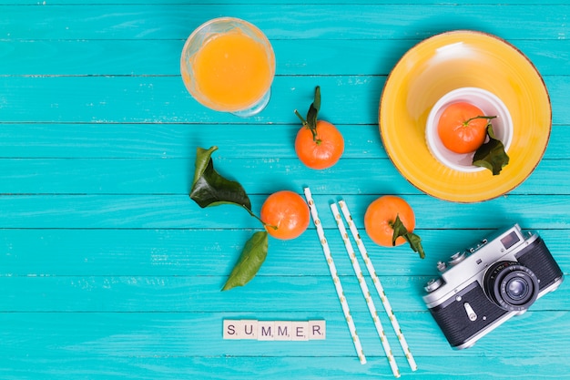 Summer set with tangerines and juice and camera on wooden surface