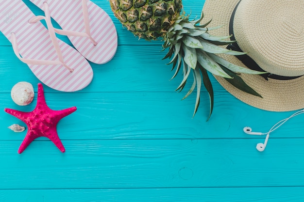 Summer surface with pineapple, flip flops and hat