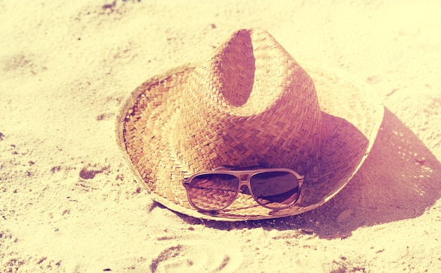 Концепция лета или каникул. Красивые солнцезащитные очки с соломенной шляпой на песке. Пляж. Стиль жизни.