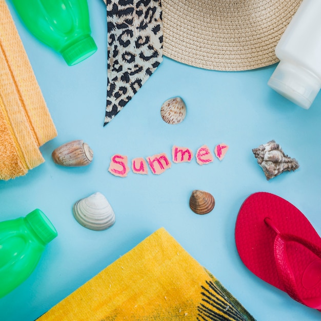 Summer word between bottles with seashells near wear and flip flop