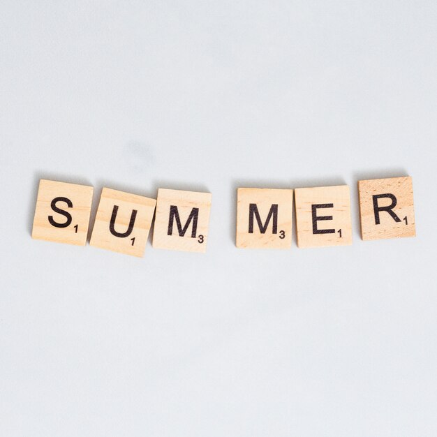 회색 표면에 나무 블록에 쓰여진 여름 단어