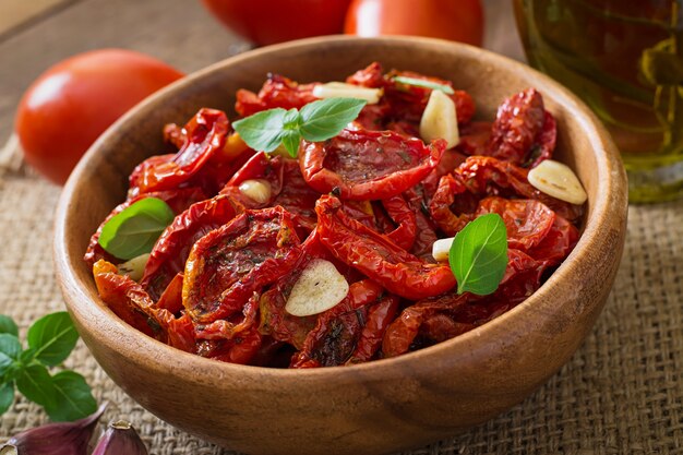 Sun-dried tomatoes with herbs and garlic in wooden bowl