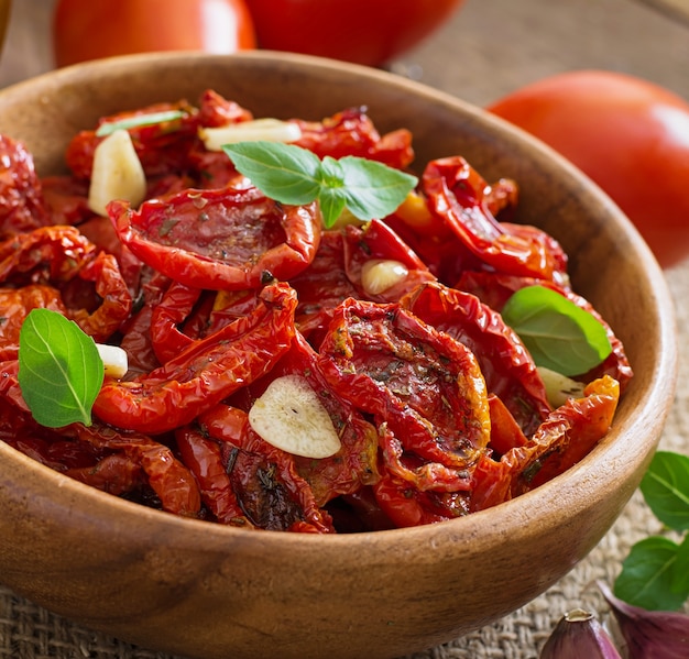 Sun-dried tomatoes with herbs and garlic in wooden bowl