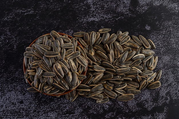 Free photo sun flower seed in a wooden bowl on the black cement floor.