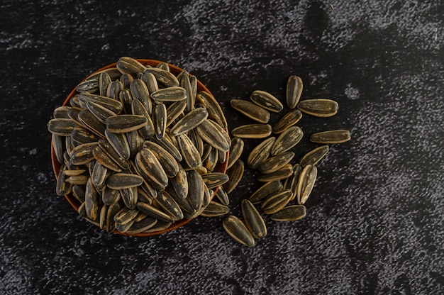 Free photo sun flower seed in a wooden bowl on the black cement floor.