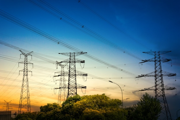 Sun setting behind the silhouette of electricity pylons