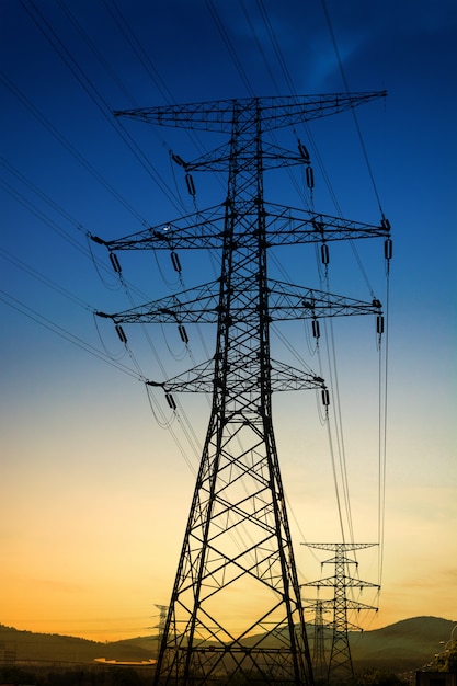 Sun setting behind the silhouette of electricity pylons