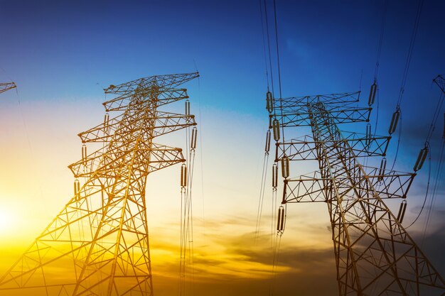 Sun setting behind the silhouette of electricity pylons