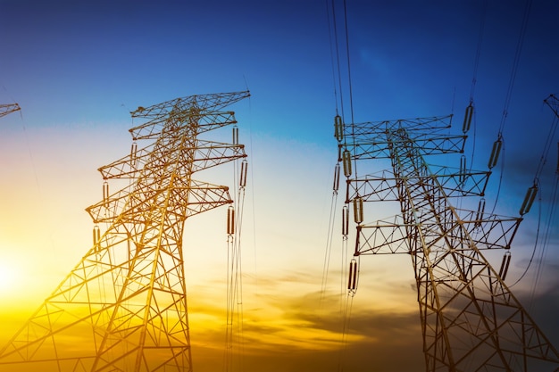 Sun setting behind the silhouette of electricity pylons