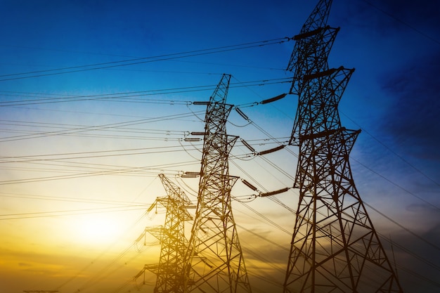 Sun setting behind the silhouette of electricity pylons