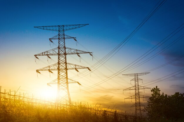 Sun setting behind the silhouette of electricity pylons