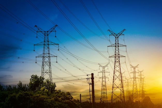 Sun setting behind the silhouette of electricity pylons