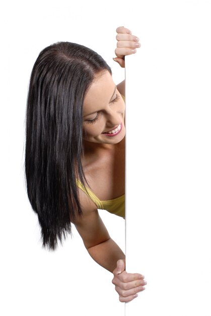 Sun tanned girl peeking round a white board