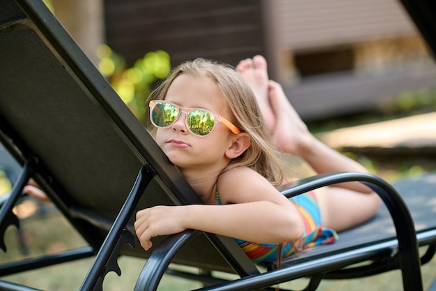 Sunbathing. Cute little blonde girl in sunglasses sunbathing