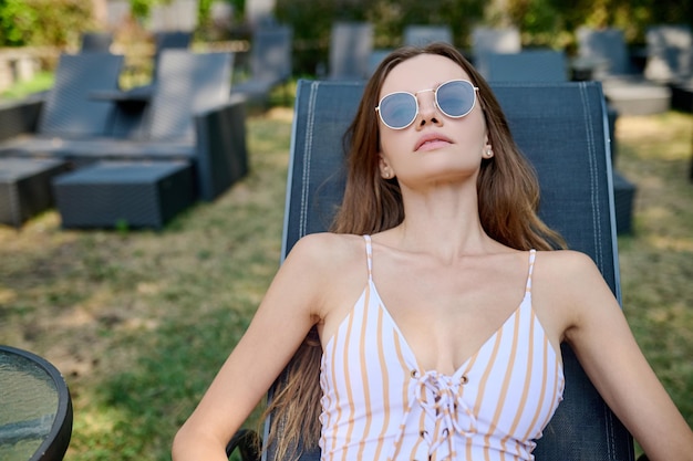 Sunbathing. A cute woman in sunglasses sunbathing and looking relaxed