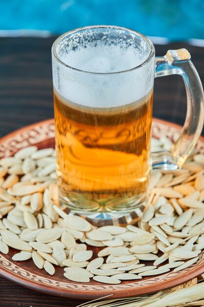 Sunflower seeds and a glass of beer on dark table.