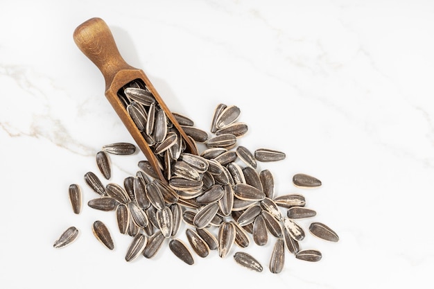 Sunflower Seeds and scoop isolated on White marble Background