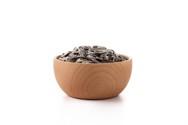 Sunflower seeds in wooden bowl isolated on white background