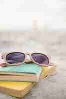 Бесплатное фото Солнцезащитные очки и книги на песке