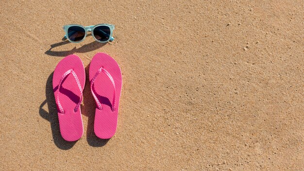 Sunglasses and beach slippers on sand