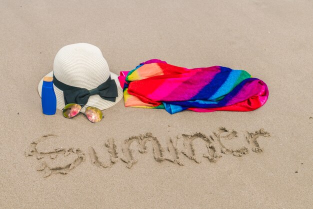 Sunglasses, sun cream and hat  on white  sand beach