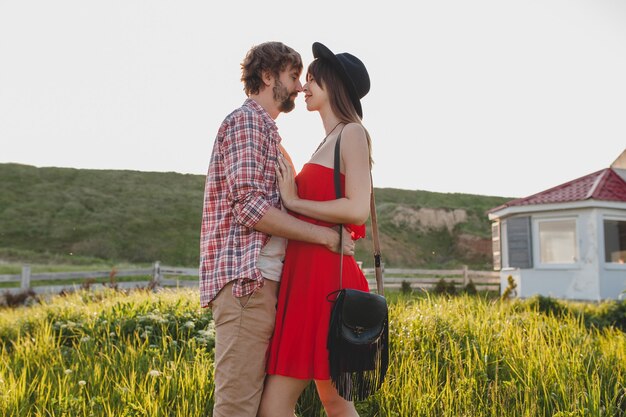 Солнечный поцелуй, обнимающий молодую стильную влюбленную пару в сельской местности, инди-хипстерский богемный стиль, каникулы на выходных, летний наряд, красное платье