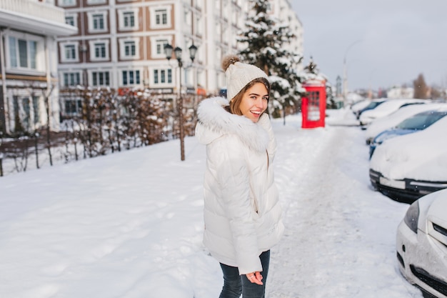 Sunny winter morning of amazing pretty woman walking on street full with snow.