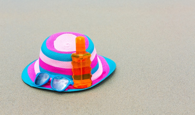 Sunscreen lotion and dark glasses with hat on the beach for summ