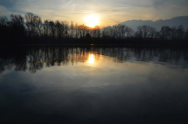 Sunset over the Alpine Lake surrounded by trees and swiss alps in the evening