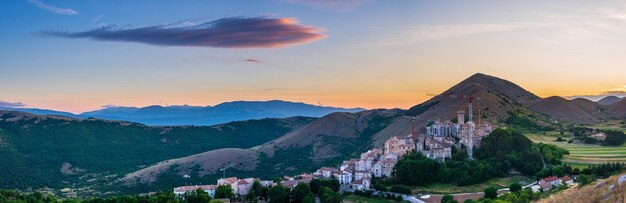 イタリア​、​アブルッツォ州​、​サントステファノディセッサーニオ​の​丘​の​上に​ある​中世​の​村​に​沈む​夕日​。​山​の​風景​、​観光地​の​上​の​ロマンチックな​空​と​雲​。