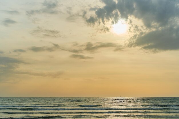 空気中の砂からの砂嵐の黄色の色合いの後の海に沈む夕日 空き領域のある海の景色の背景